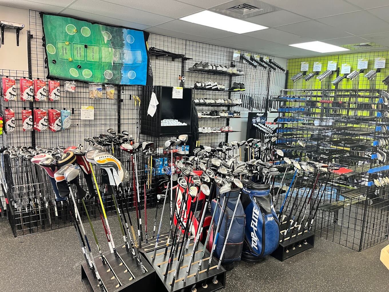 The interior of Play It Again Sports in Lakewood featuring the golf section of the store with neatly placed golf clubs with head covers and golf bags ready for sale.