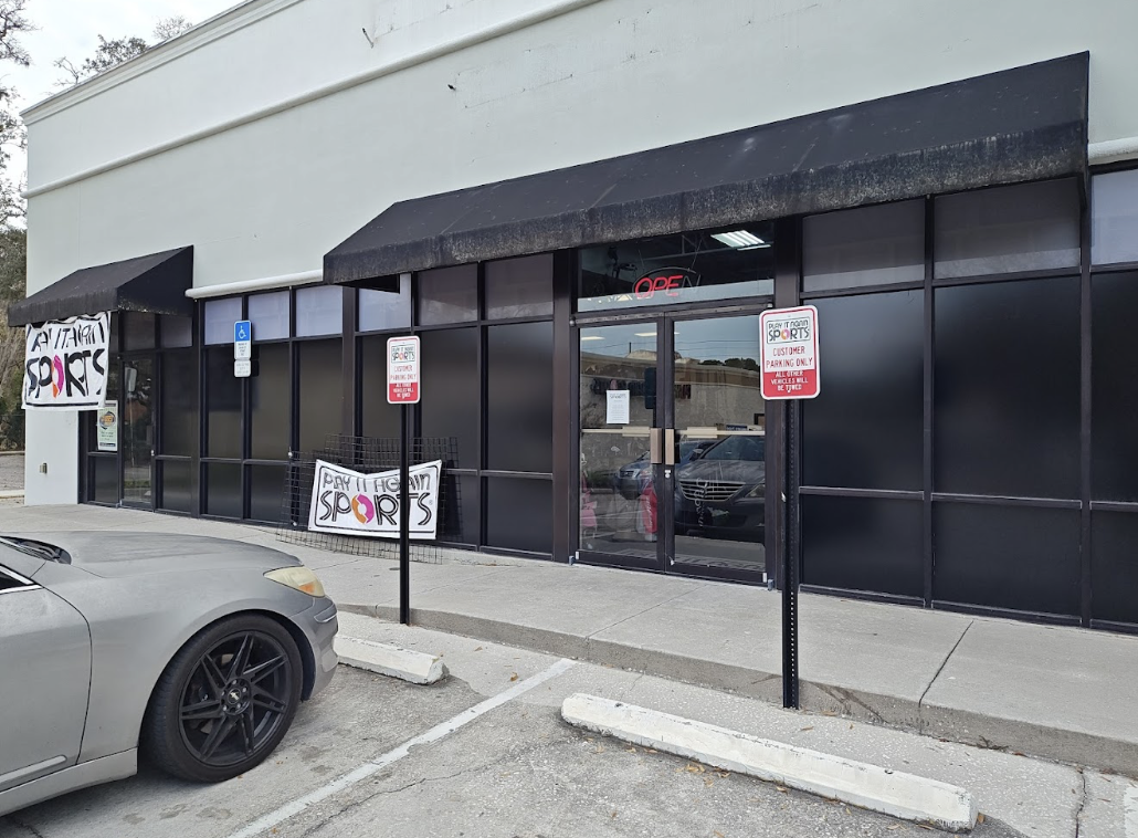 The outside of the new location for the Play It Again Sports in Altamonte Springs. It's a grey and black building with Play It Again Sports signs hanging on the side of the building.