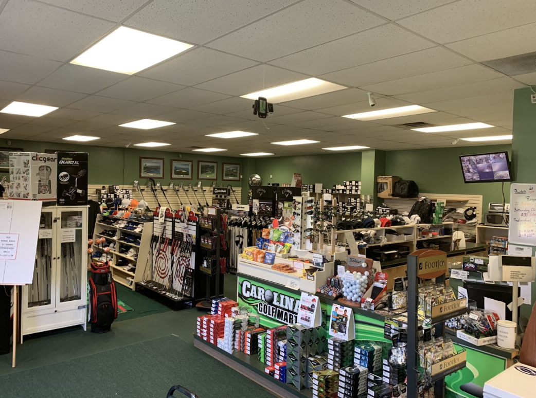The inside of Carolina Golf Mart & Practice which features green floors and walls and shelves of golf related merchandise.