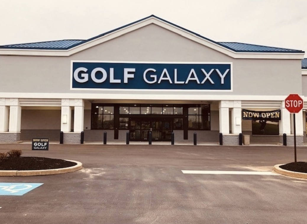 The front of the Golf Galaxy store. It's a grey building with a big dark blue sign displaying the name of the store.