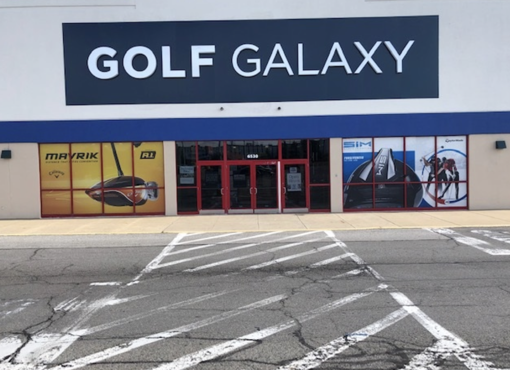 The outside of Golf Galaxy features a big navy blue sign with white writing displaying the name of the store and big advertisements in the windows.